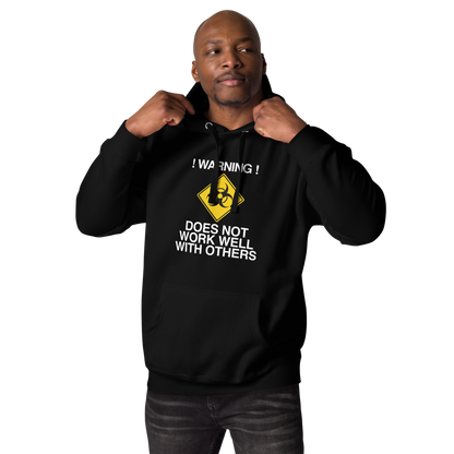 "!Warning! Does Not Work Well With Others" printed on a black unisex hoodie worn by a male