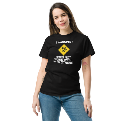 "!Warning! Does Not Work Well With Others" printed on a black unisex classic tee worn by a female