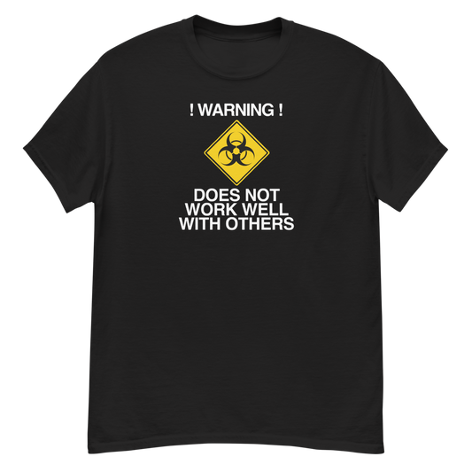 "!Warning! Does Not Work Well With Others" printed on a black unisex classic tee laying on a flat surface