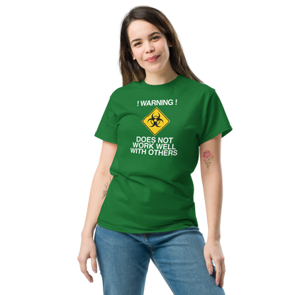 "!Warning! Does Not Work Well With Others" printed on a turf green unisex classic tee worn by a female