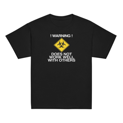 "!Warning! Does Not Work Well With Others" printed on a black youth classic tee laying on a flat surface