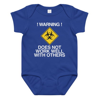 "!Warning! Does Not Work Well With Others" printed on a royal baby jersey bodysuit laying on a flat surface amongst other clothes