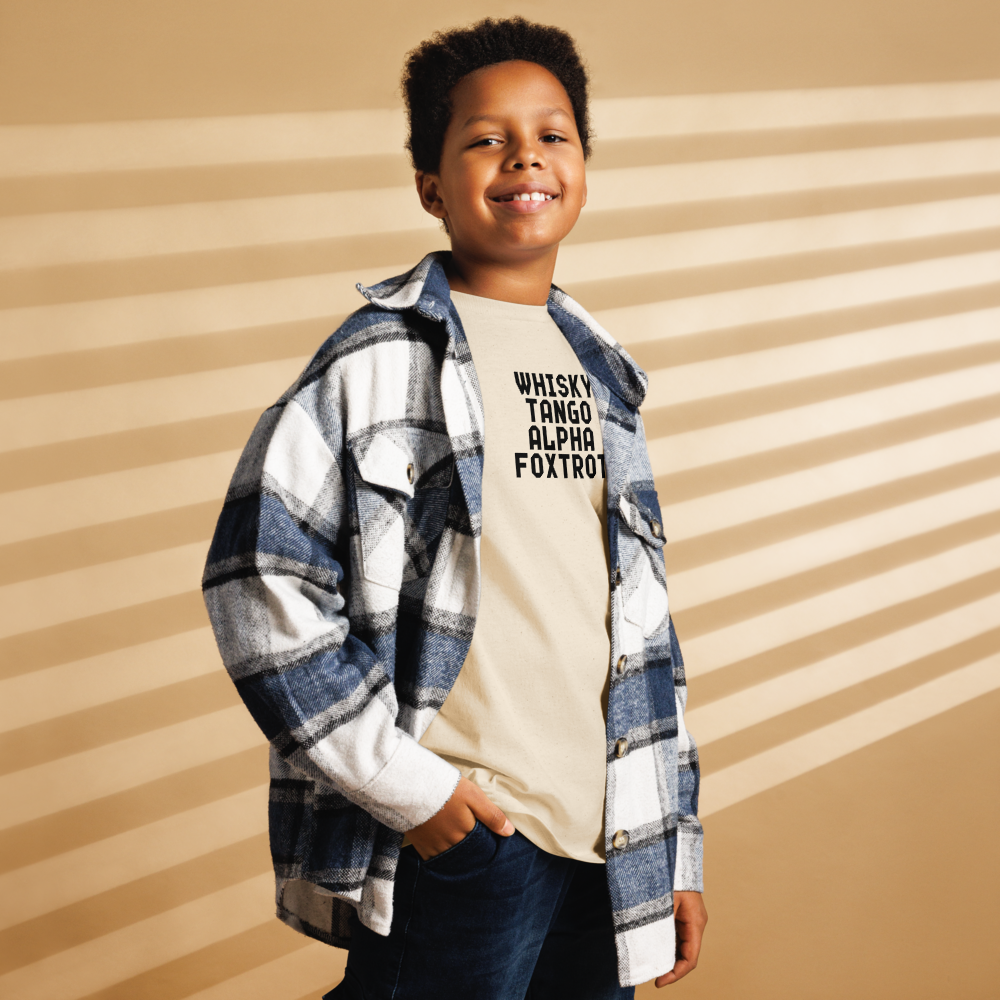 "Whisky Tango Alpha Foxtrot" printed on a natural youth classic tee worn by a male also wearing a jacket