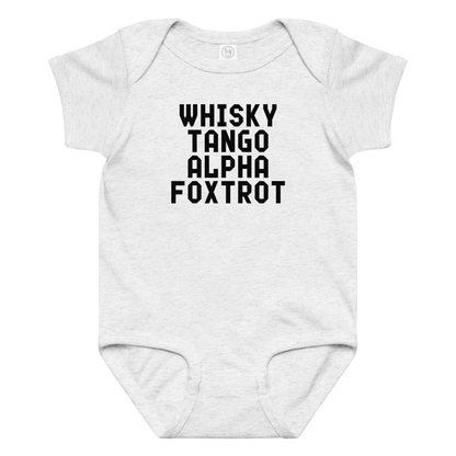 "Whisky Tango Alpha Foxtrot" printed on a ash baby jersey bodysuit laying on a flat surface amongst other clothes