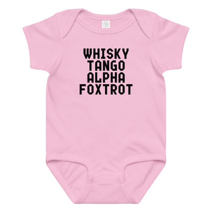 "Whisky Tango Alpha Foxtrot" printed on a pink baby jersey bodysuit laying on a flat surface amongst other clothes