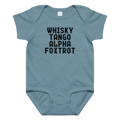 "Whisky Tango Alpha Foxtrot" printed on a vintage indigo baby jersey bodysuit laying on a flat surface amongst other clothes