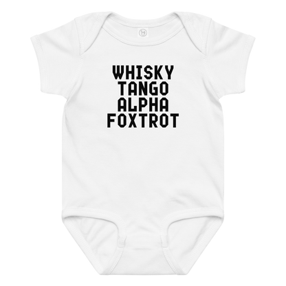 "Whisky Tango Alpha Foxtrot" printed on a white baby jersey bodysuit laying on a flat surface amongst other clothes