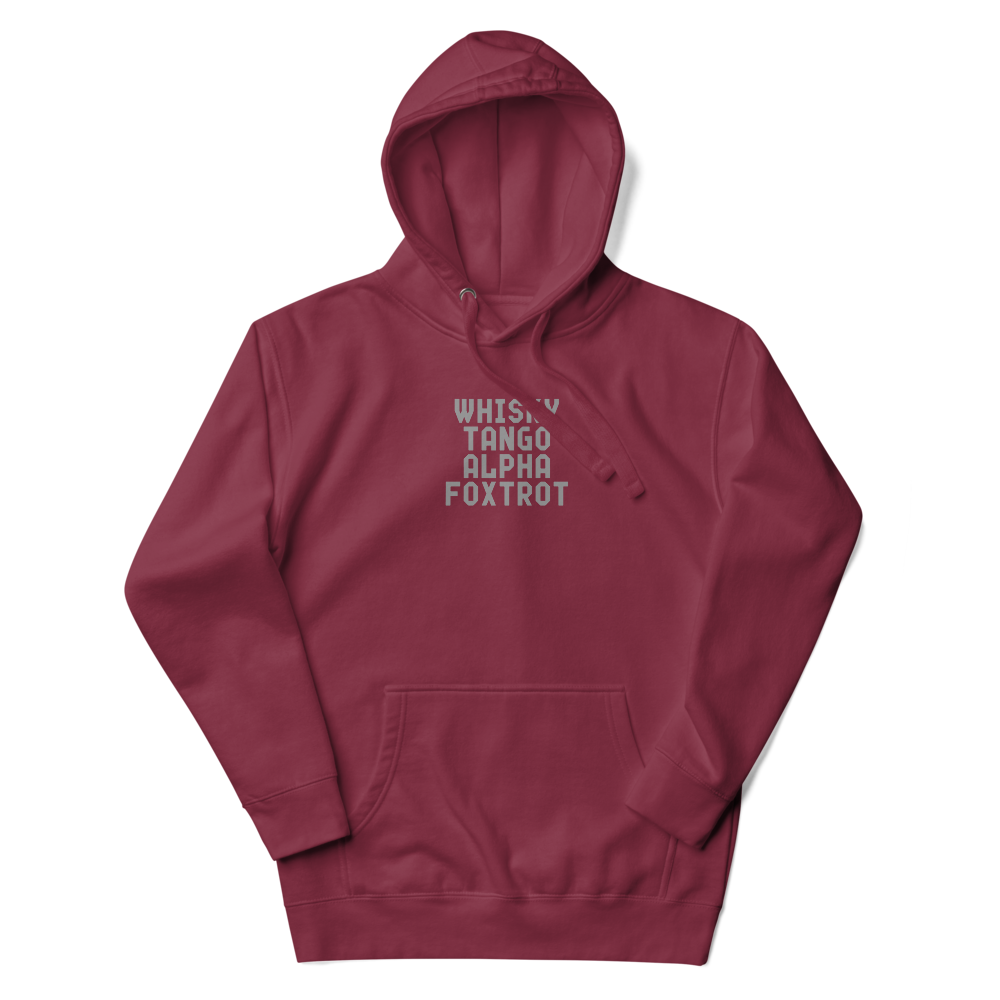 "Whisky Tango Alpha Foxtrot" printed on a maroon unisex hoodie laying on a flat surface with the hood up