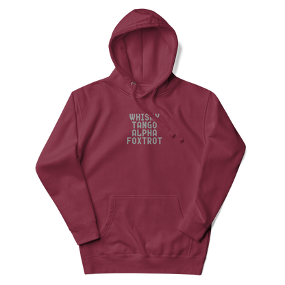 "Whisky Tango Alpha Foxtrot" printed on a maroon unisex hoodie laying on a flat surface with the hood up