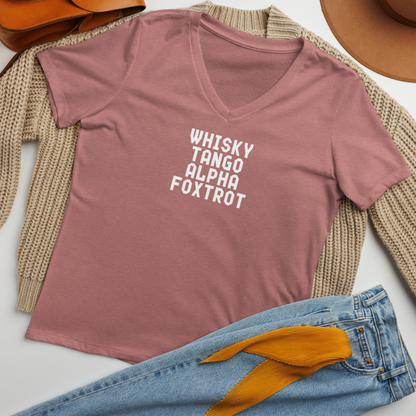 "Whisky Tango Alpha Foxtrot" printed on a heather mauve women's relaxed v-neck t-shirt laying on a flat surface amongst other clothes