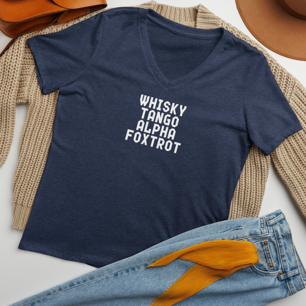 "Whisky Tango Alpha Foxtrot" printed on a heather navy women's relaxed v-neck t-shirt laying on a flat surface amongst other clothes