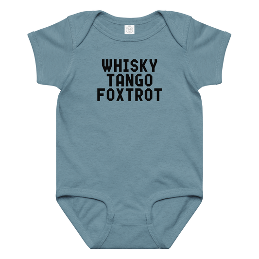 "Whisky Tango Foxtrot (What the f#ck)" printed on a vintage indigo baby jersey bodysuit laying on a flat surface amongst other clothes