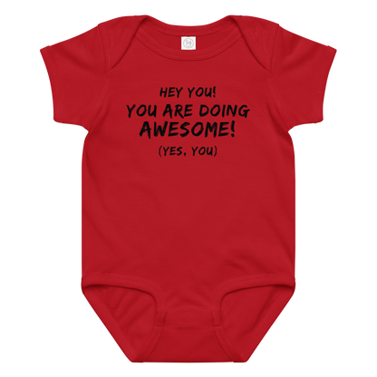 "Hey You! You are doing awesome! (Yes, you)" printed on a red baby jersey bodysuit laying on a flat surface amongst other clothes