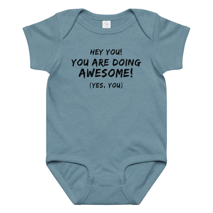 "Hey You! You are doing awesome! (Yes, you)" printed on a vintage indigo baby jersey bodysuit laying on a flat surface amongst other clothes