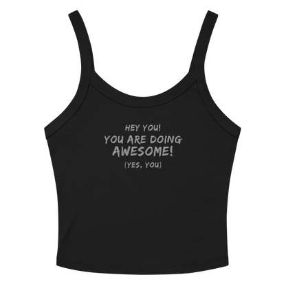 "Hey You! You are doing awesome! (Yes, you)" printed on a solid black blend women's micro-rib tanktop laying on a flat surface amongst sunglasses and shorts