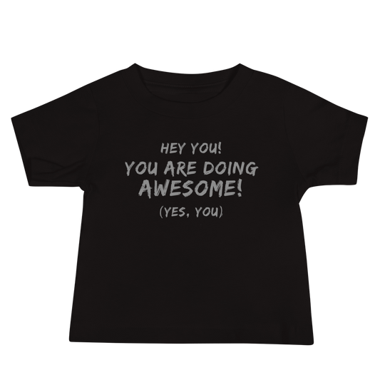 "Hey You! You are doing awesome! (Yes, you)" printed on a black baby jersey short sleeve tee laying on a flat surface