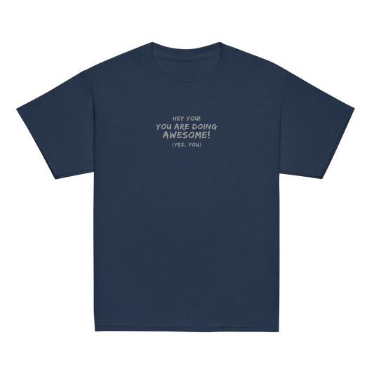 "Hey You! You are doing awesome! (Yes, you)" printed on a navy youth classic tee laying on a flat surface