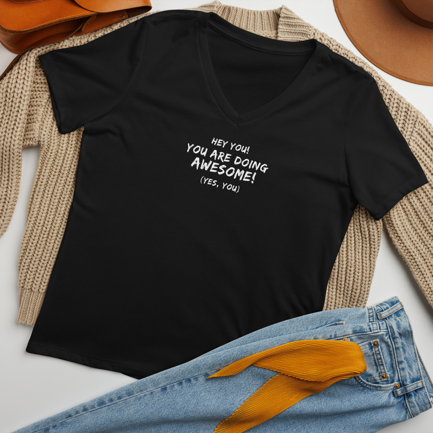 "Hey You! You are doing awesome! (Yes, you)" printed on a solid black blend women's relaxed v-neck t-shirt laying on a flat surface amongst other clothes