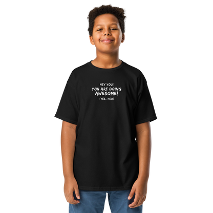 "Hey You! You are doing awesome! (Yes, you)" printed on a black youth classic tee worn by a male