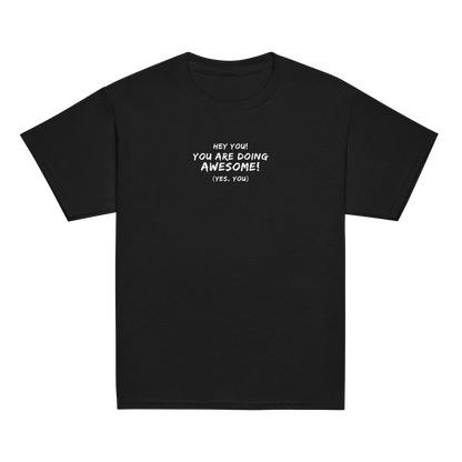 "Hey You! You are doing awesome! (Yes, you)" printed on a black youth classic tee laying on a flat surface