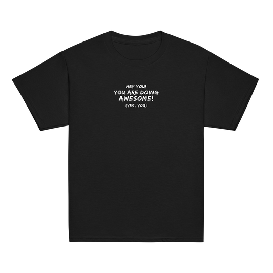 "Hey You! You are doing awesome! (Yes, you)" printed on a black youth classic tee laying on a flat surface