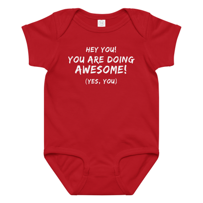 "Hey You! You are doing awesome! (Yes, you)" printed on a red baby jersey bodysuit laying on a flat surface amongst other clothes