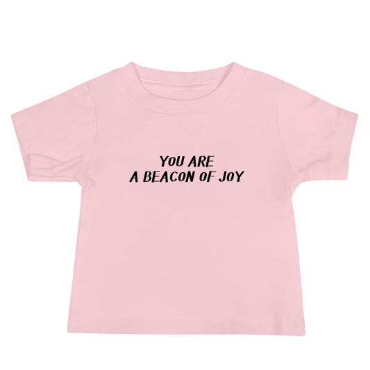 "You are a beacon of joy" printed on a pink baby jersey short sleeve tee laying on a flat surface