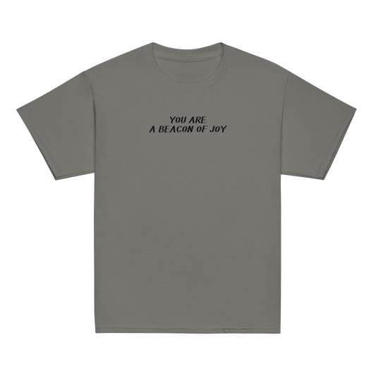 "You are a beacon of joy" printed on a charcoal youth classic tee laying on a flat surface