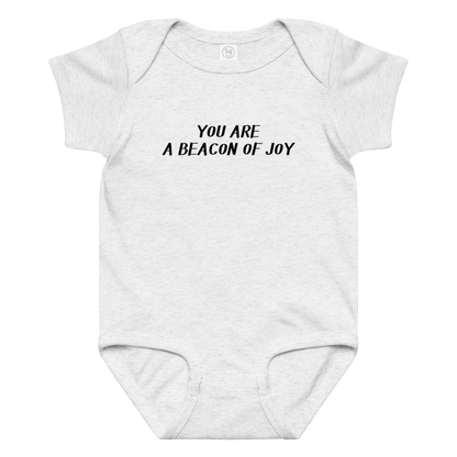 "You are a beacon of joy" printed on a ash baby jersey bodysuit laying on a flat surface amongst other clothes