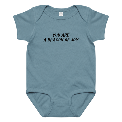 "You are a beacon of joy" printed on a vintage indigo baby jersey bodysuit laying on a flat surface amongst other clothes