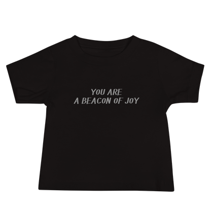"You are a beacon of joy" printed on a black baby jersey short sleeve tee laying on a flat surface