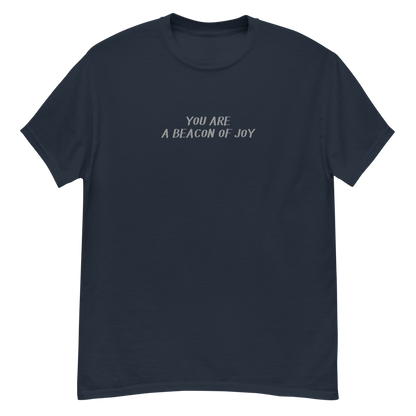 "You are a beacon of joy" printed on a navy unisex classic tee laying on a flat surface