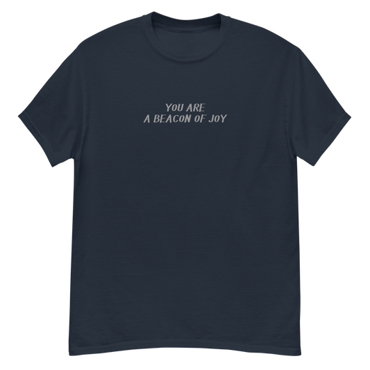 "You are a beacon of joy" printed on a navy unisex classic tee laying on a flat surface