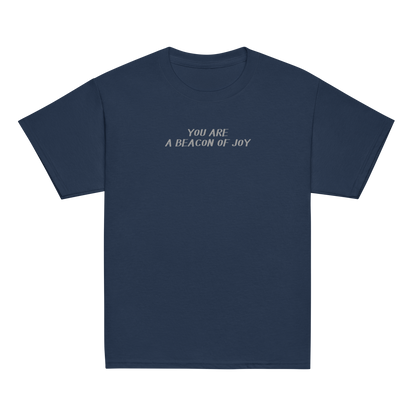"You are a beacon of joy" printed on a navy youth classic tee laying on a flat surface