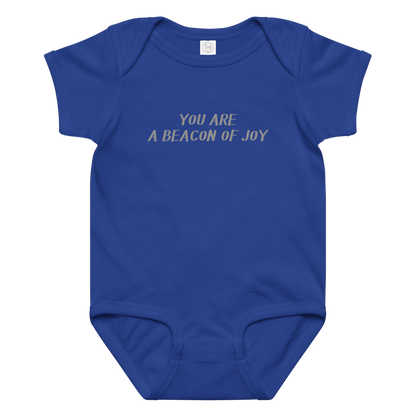 "You are a beacon of joy" printed on a royal baby jersey bodysuit laying on a flat surface amongst other clothes
