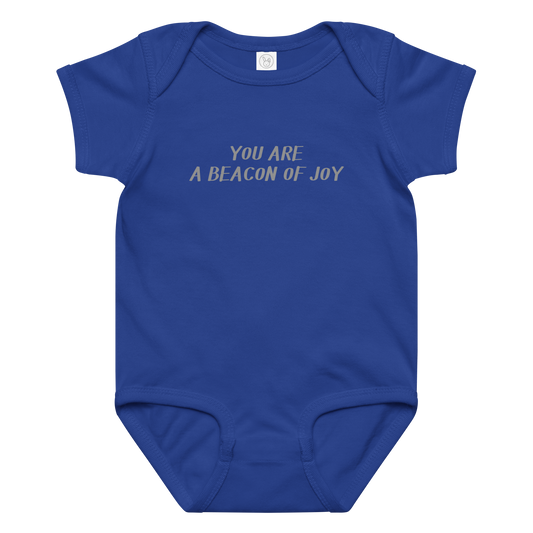"You are a beacon of joy" printed on a royal baby jersey bodysuit laying on a flat surface amongst other clothes