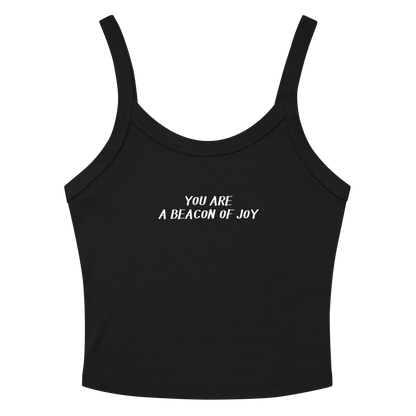 "You are a beacon of joy" printed on a solid black blend women's micro-rib tanktop laying on a flat surface amongst sunglasses and shorts