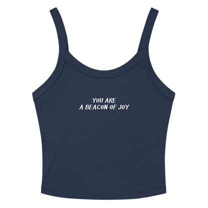 "You are a beacon of joy" printed on a solid navy blend women's micro-rib tanktop laying on a flat surface amongst sunglasses and shorts