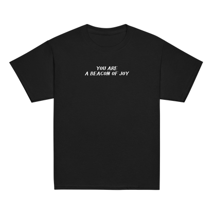 "You are a beacon of joy" printed on a black youth classic tee laying on a flat surface