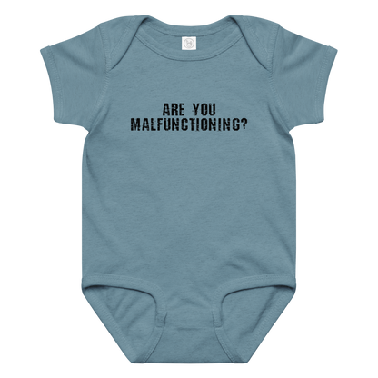 "Are you malfunctioning?" printed on a vintage indigo baby jersey bodysuit laying on a flat surface amongst other clothes