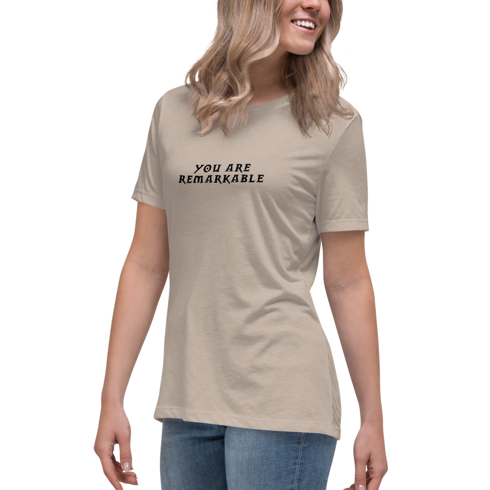 "You are remarkable" printed on a heather stone women's relaxed t-shirt worn by a female