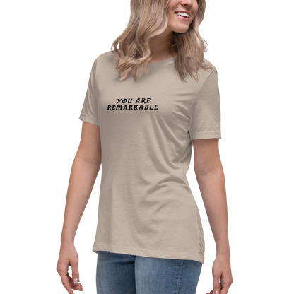 "You are remarkable" printed on a heather stone women's relaxed t-shirt worn by a female