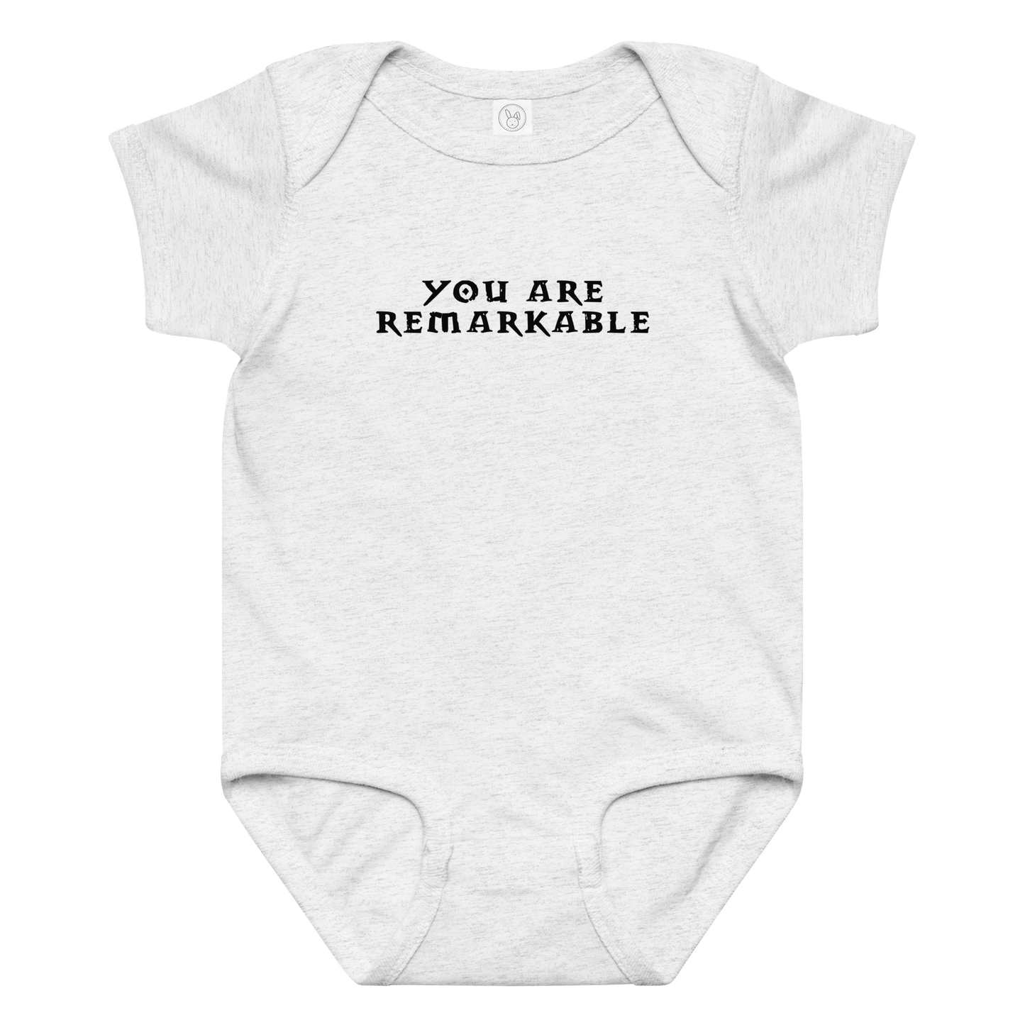 "You are remarkable" printed on a ash baby jersey bodysuit laying on a flat surface amongst other clothes