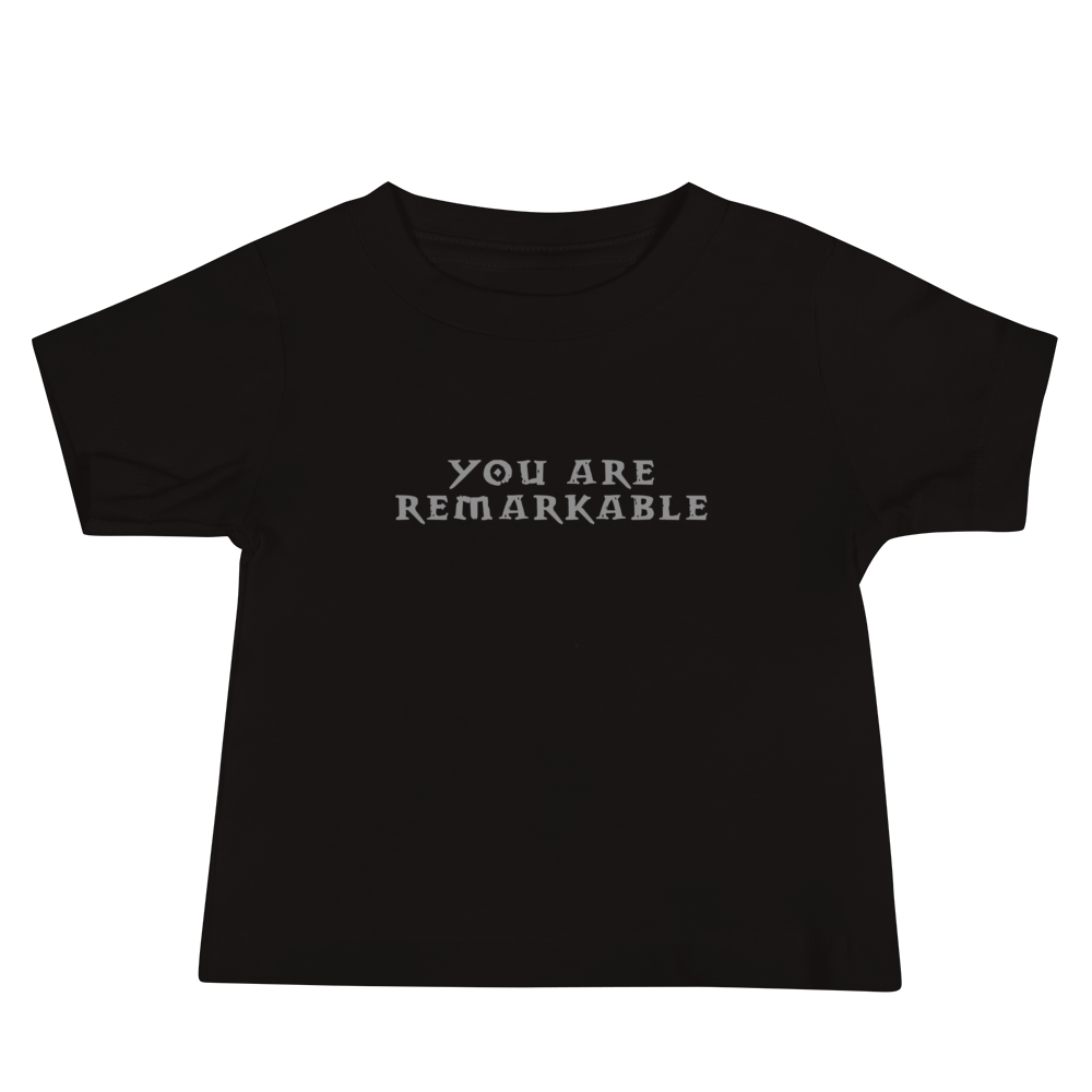 "You are remarkable" printed on a black baby jersey short sleeve tee laying on a flat surface