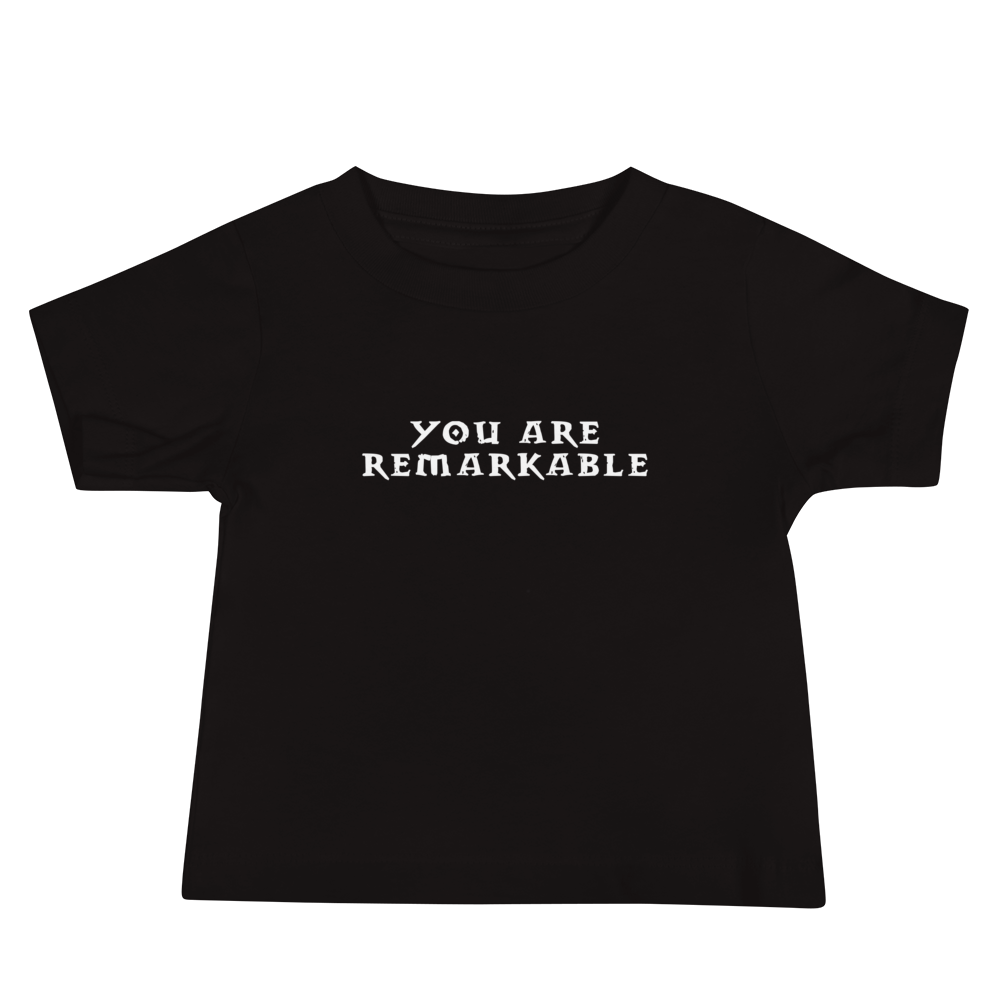 "You are remarkable" printed on a black baby jersey short sleeve tee laying on a flat surface