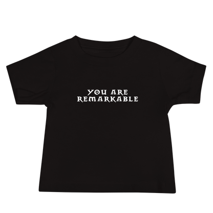 "You are remarkable" printed on a black baby jersey short sleeve tee laying on a flat surface