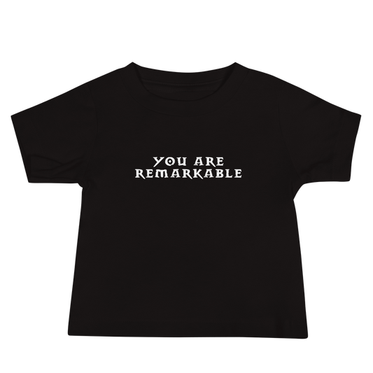 "You are remarkable" printed on a black baby jersey short sleeve tee laying on a flat surface