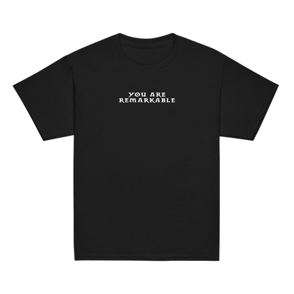 "You are remarkable" printed on a black youth classic tee laying on a flat surface
