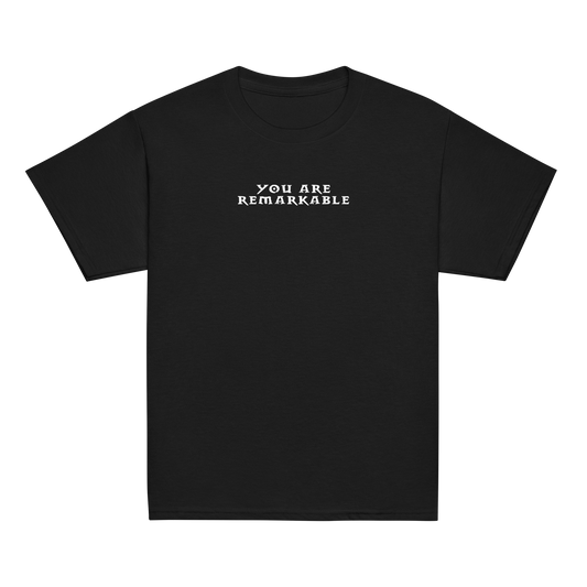 "You are remarkable" printed on a black youth classic tee laying on a flat surface