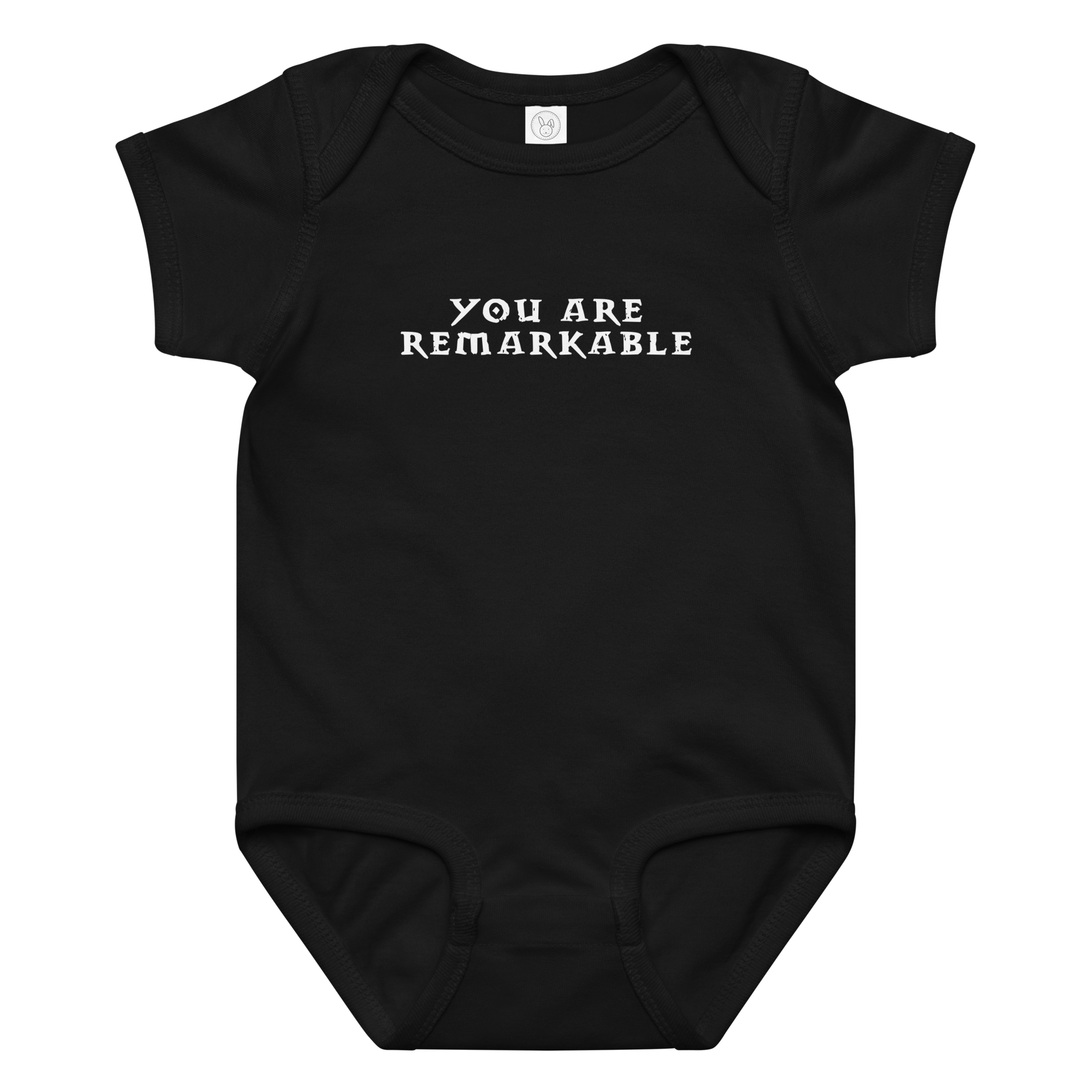 "You are remarkable" printed on a black baby jersey bodysuit laying on a flat surface amongst other clothes